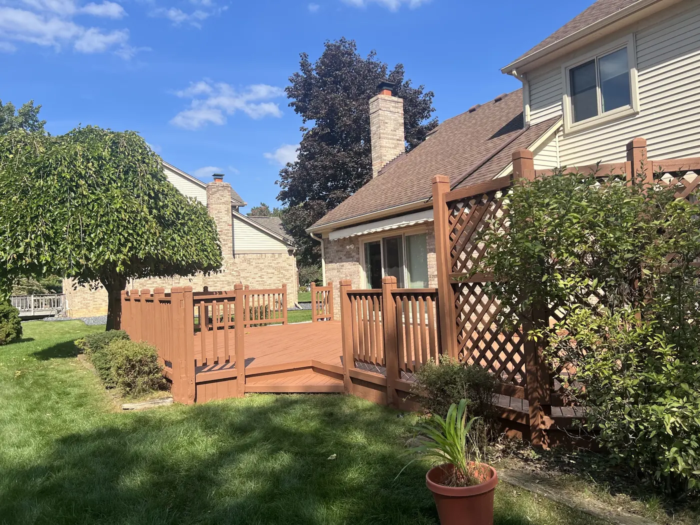 A stained deck and lattice screen seen from the lawn on a bright day.