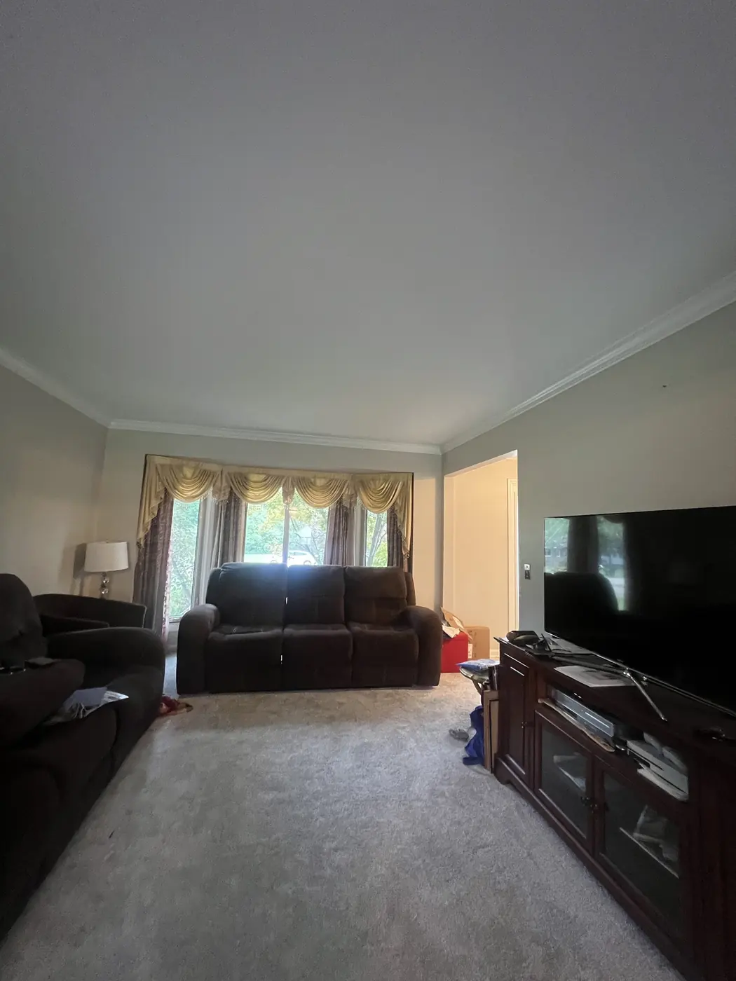 A living room with warm painted walls, trim and a wide front window.
