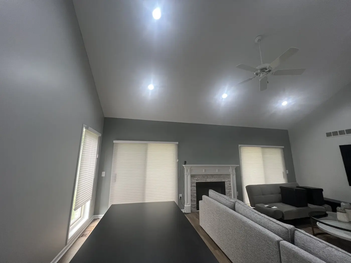 A living room in soft grey with a white fireplace surround and vaulted ceiling.