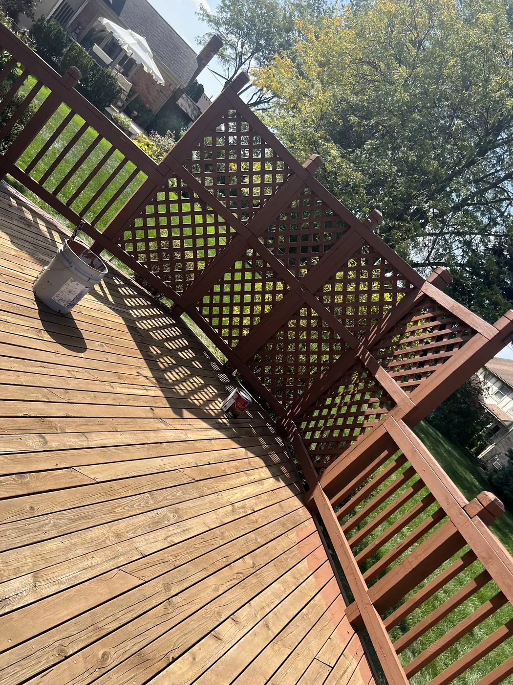 The same style of deck mid-project, boards stripped back to bare wood with lattice panels set aside.