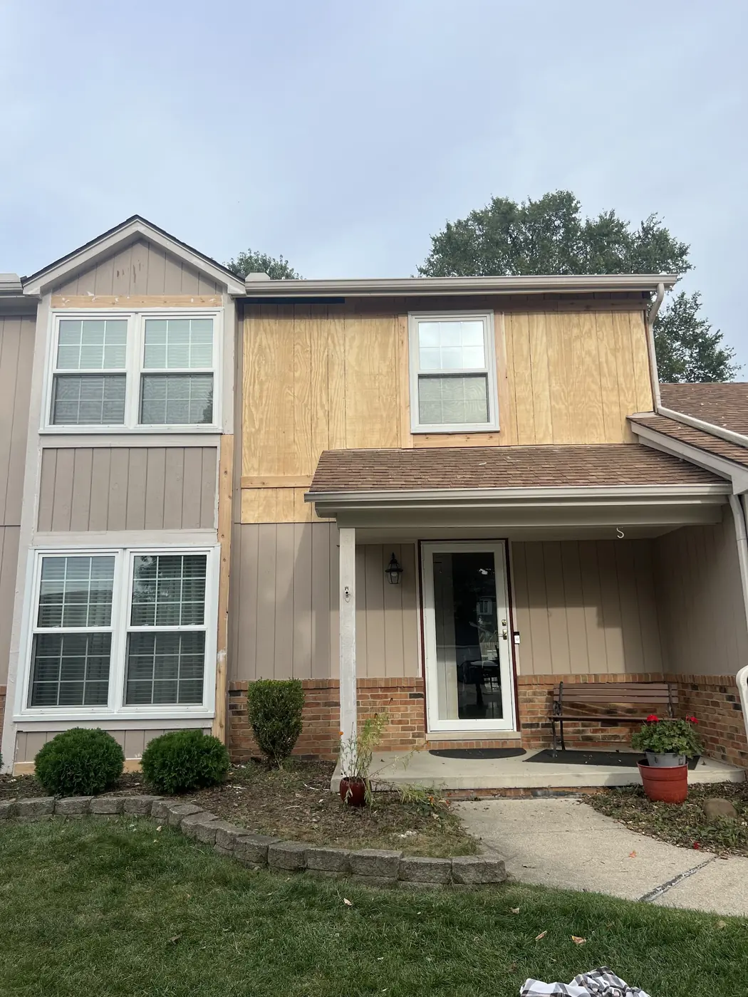 The front of a house with siding partly replaced, new board sections in place before finishing.