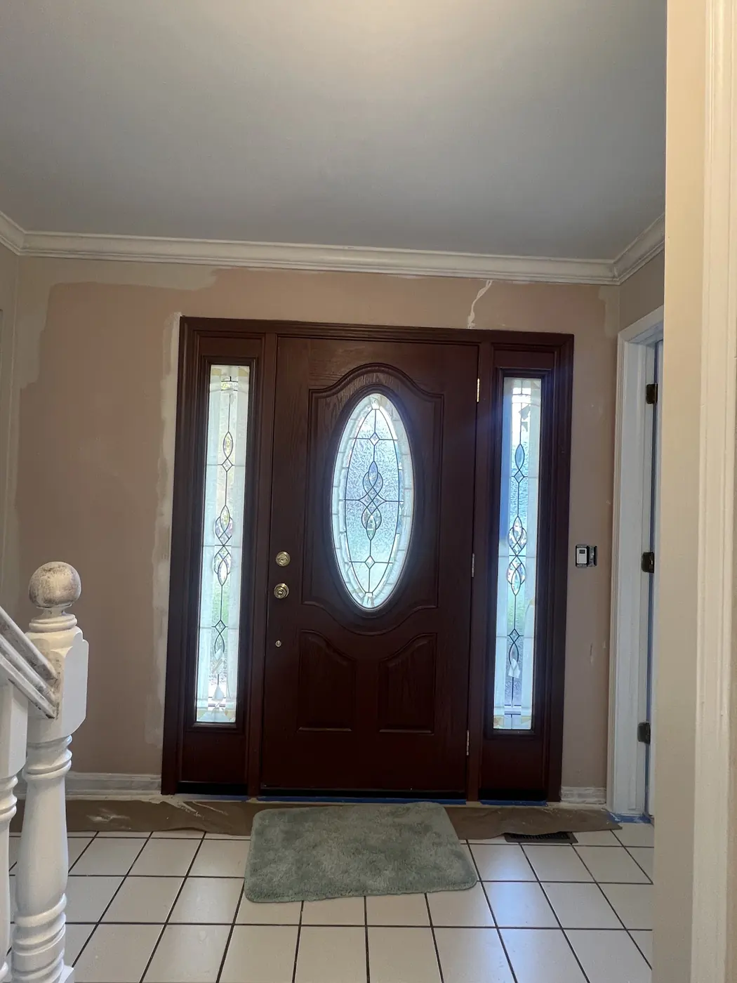 A front entry with a stained wood door, sidelights and pale walls.