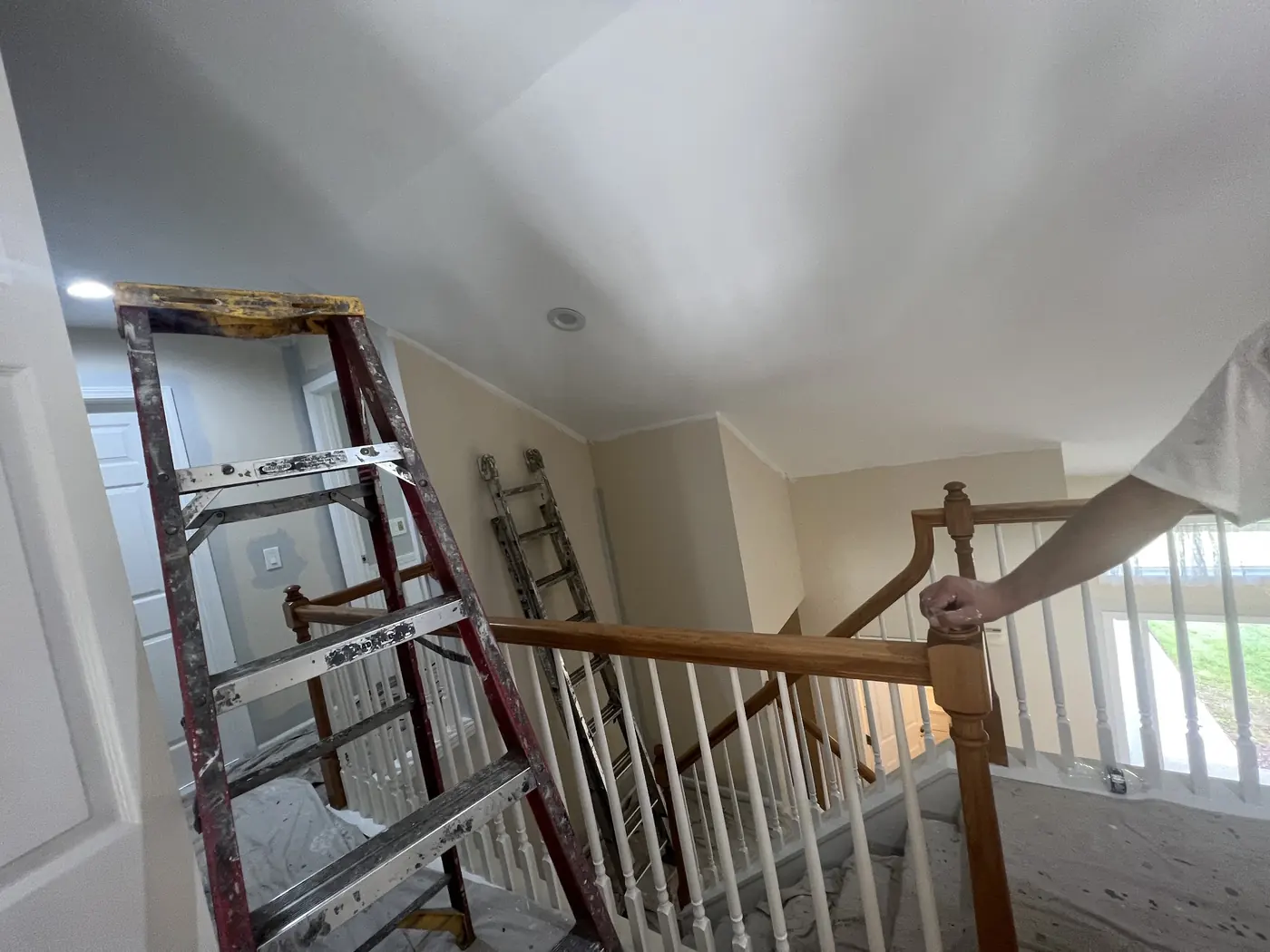 A stairwell painted out in white, a step ladder still standing against the wall.